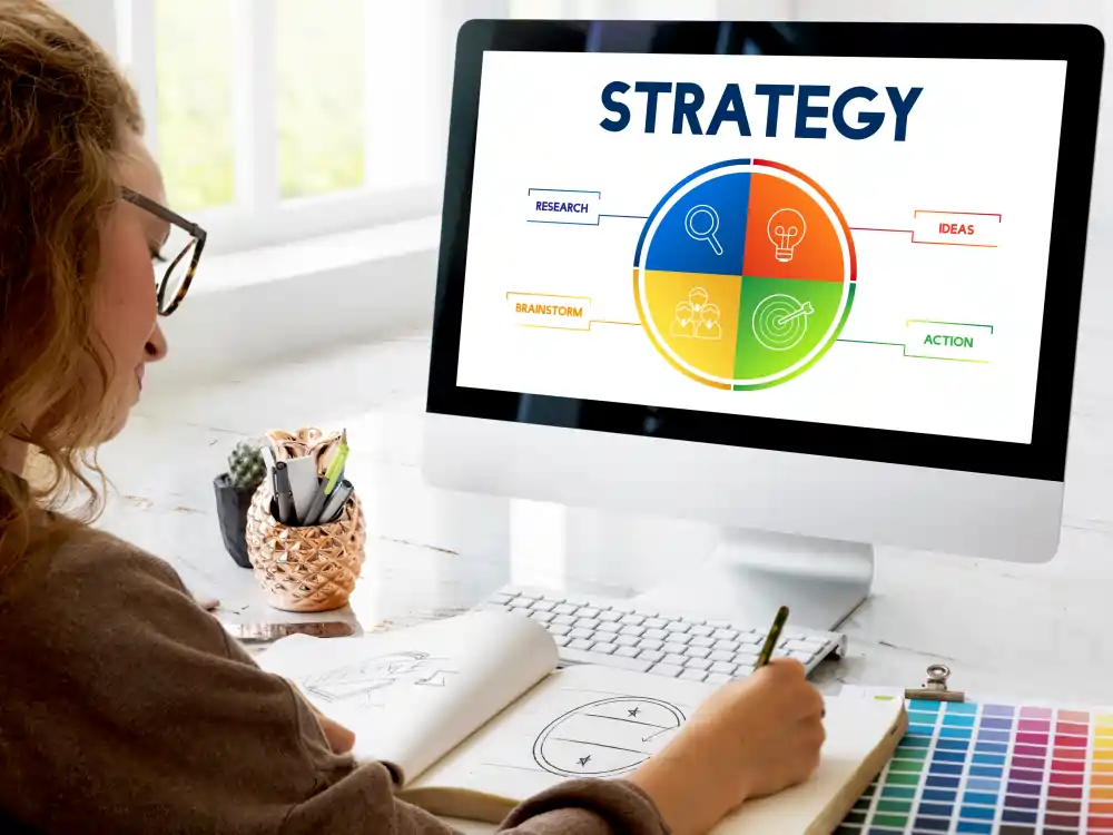 strategie-digitale-optimisation-anval Femme travaillant sur une stratégie digitale avec un plan d’action affiché sur un écran.